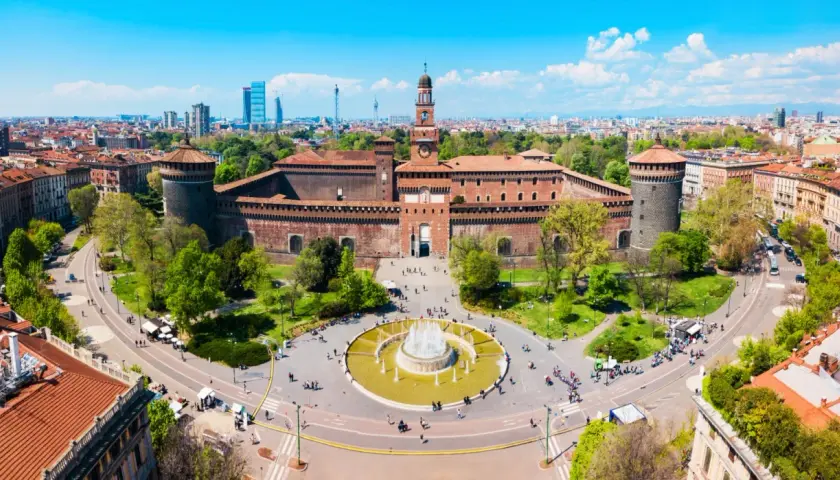 Il castello di Milano, imponente e storico, si erge maestoso con le sue torri e il cortile animato da visitatori.