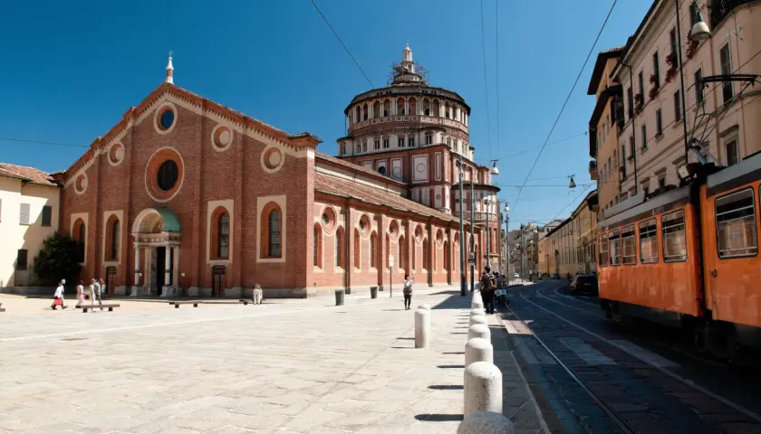 Piazza antistante Santa Maria delle Grazie con tram arancione in transito.