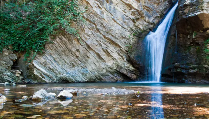 Cascate in Basilicata: acqua cristallina scende da rocce stratificate, circondate da vegetazione lussureggiante. Un angolo di paradiso naturale.