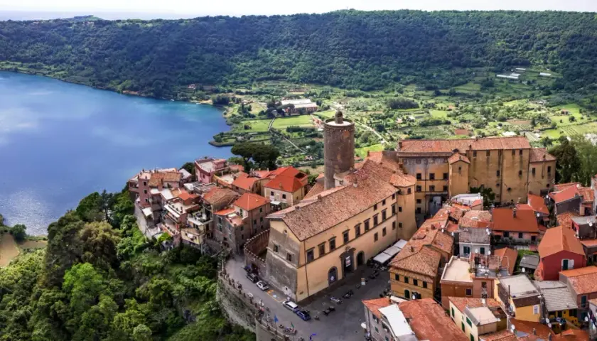 Nemi, un gioiello sui Castelli Romani, si affaccia sul lago. Case con tetti rossi si aggrappano alla collina, con una torre medievale che domina il panorama.