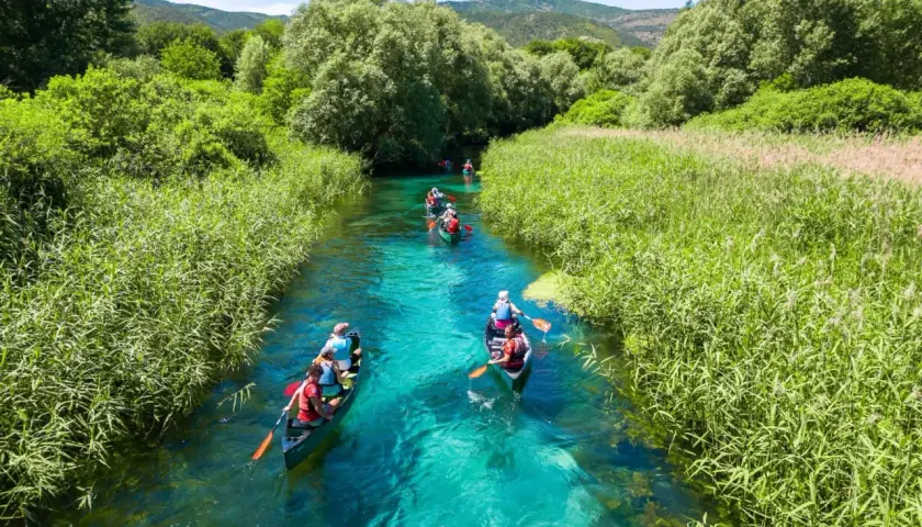 Persone in canoa su un fiume cristallino, un'ottima idea per visitare l'Abruzzo con itinerari naturalistici.