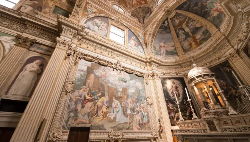 Interior of a church with ornate frescoes depicting religious scenes on walls and ceiling.