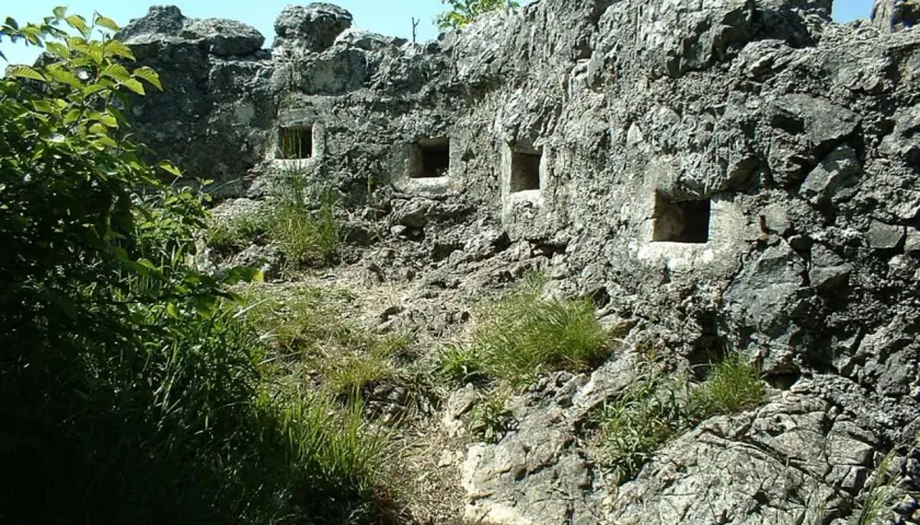 Antiche trincee della Linea Cadorna scavate nella roccia, con feritoie che si affacciano su un paesaggio verdeggiante.