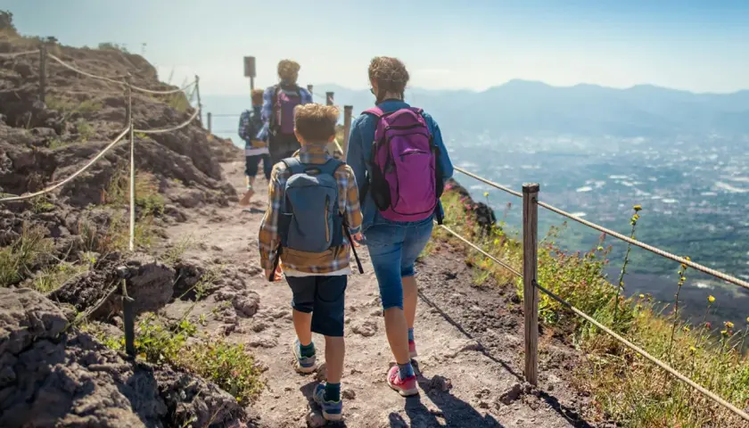 Famiglia in escursione sul sentiero del **Parco Nazionale del Vesuvio**, con vista panoramica sulla costa.