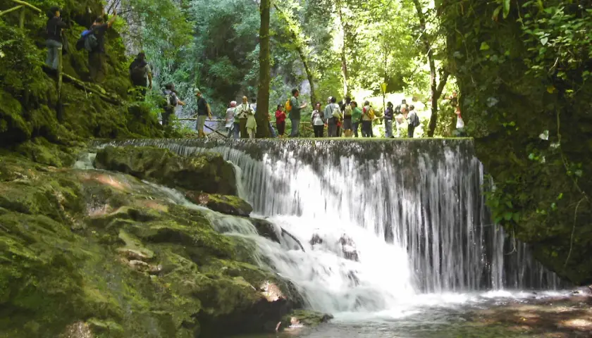 Cascata nella Valle delle Ferriere ad Amalfi, con un gruppo di escursionisti che osserva il panorama.