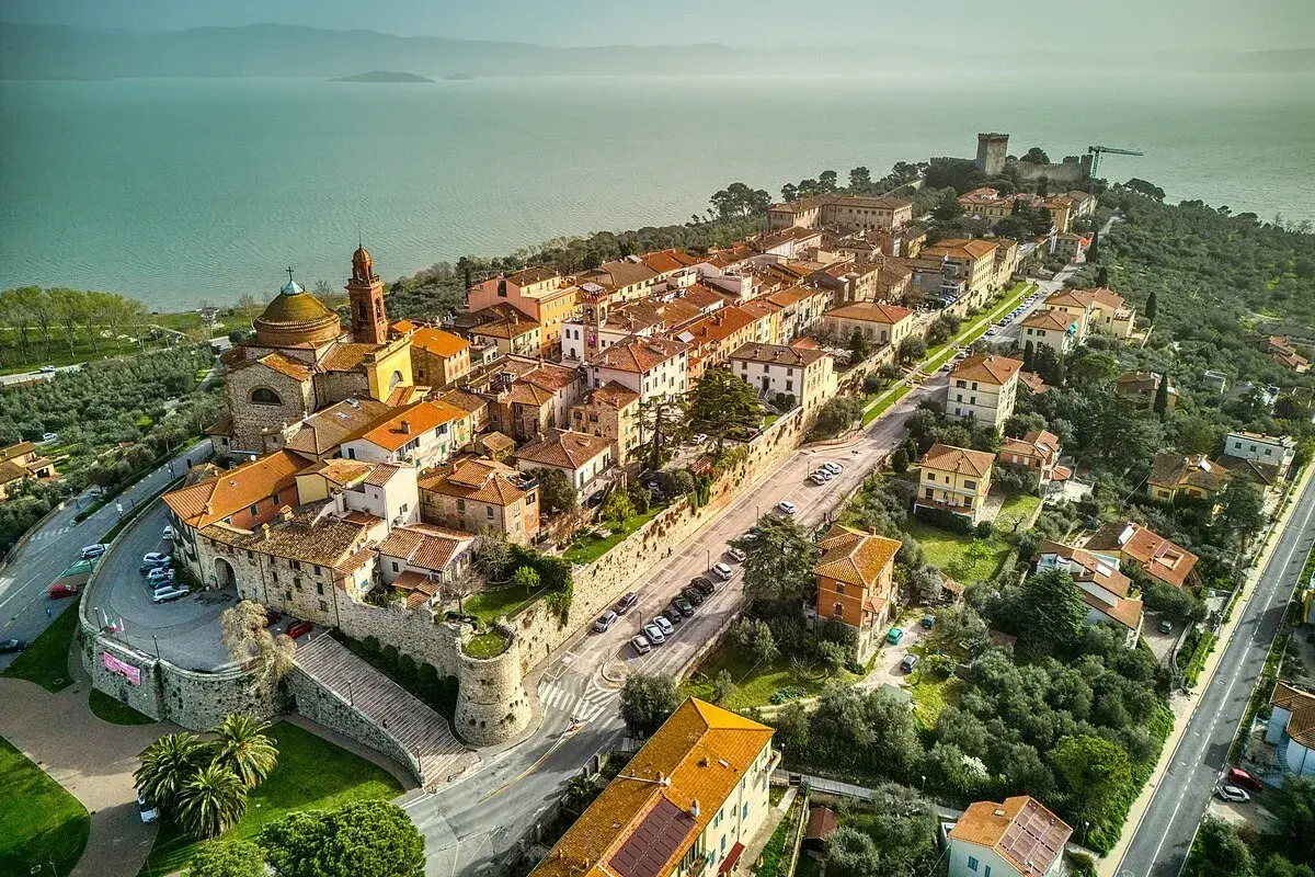 Vista aerea di Castiglione del Lago, un borgo medievale con tetti arancioni affacciato sul lago Trasimeno.