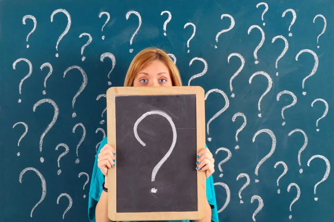 Ragazza con lavagna piena di punti interrogativi, come per le prove invalsi che sono obbligatorie.