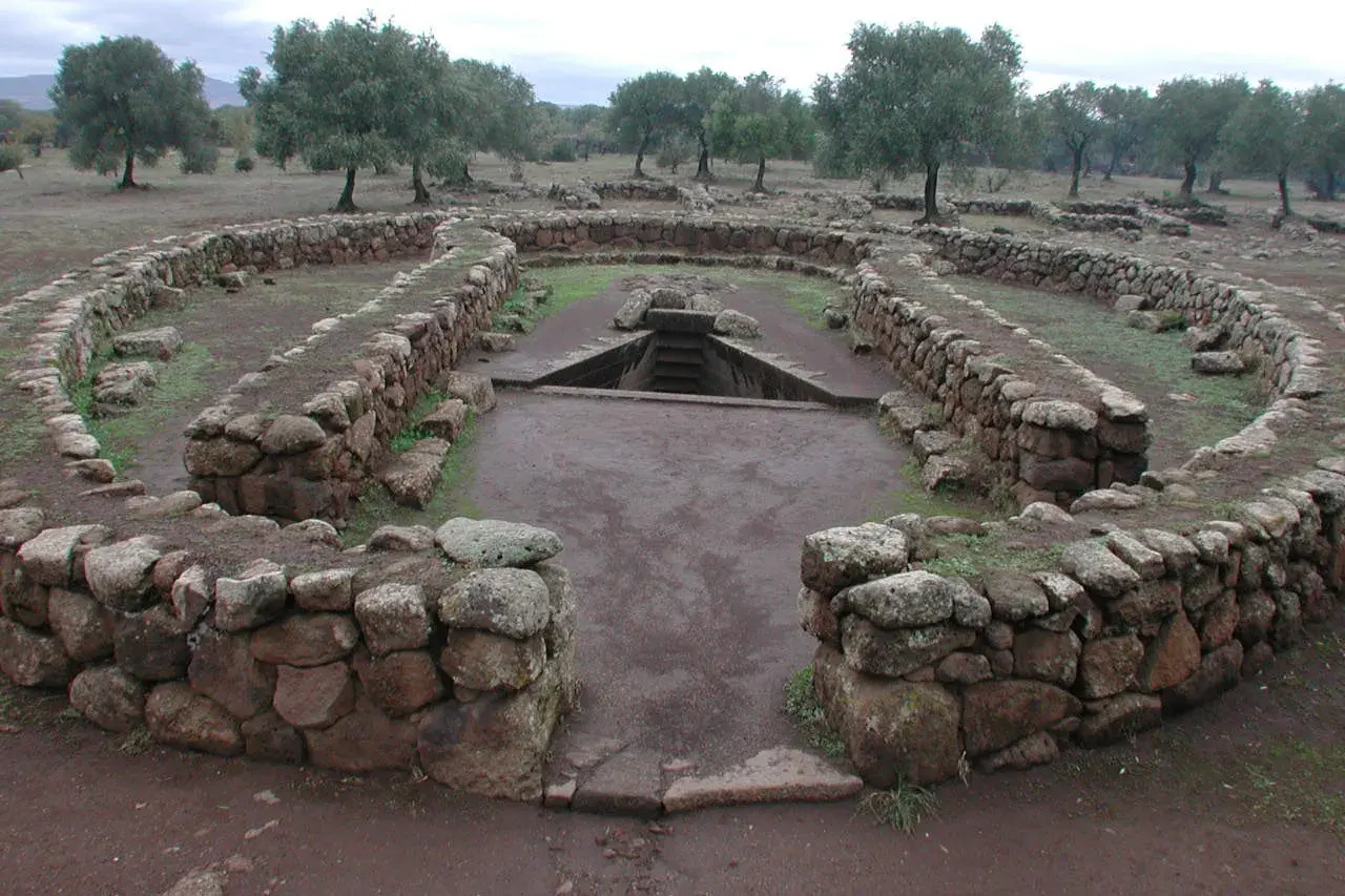 Antichi pozzi sacri in Sardegna, con mura in pietra a secco e una scala che scende nell'acqua.