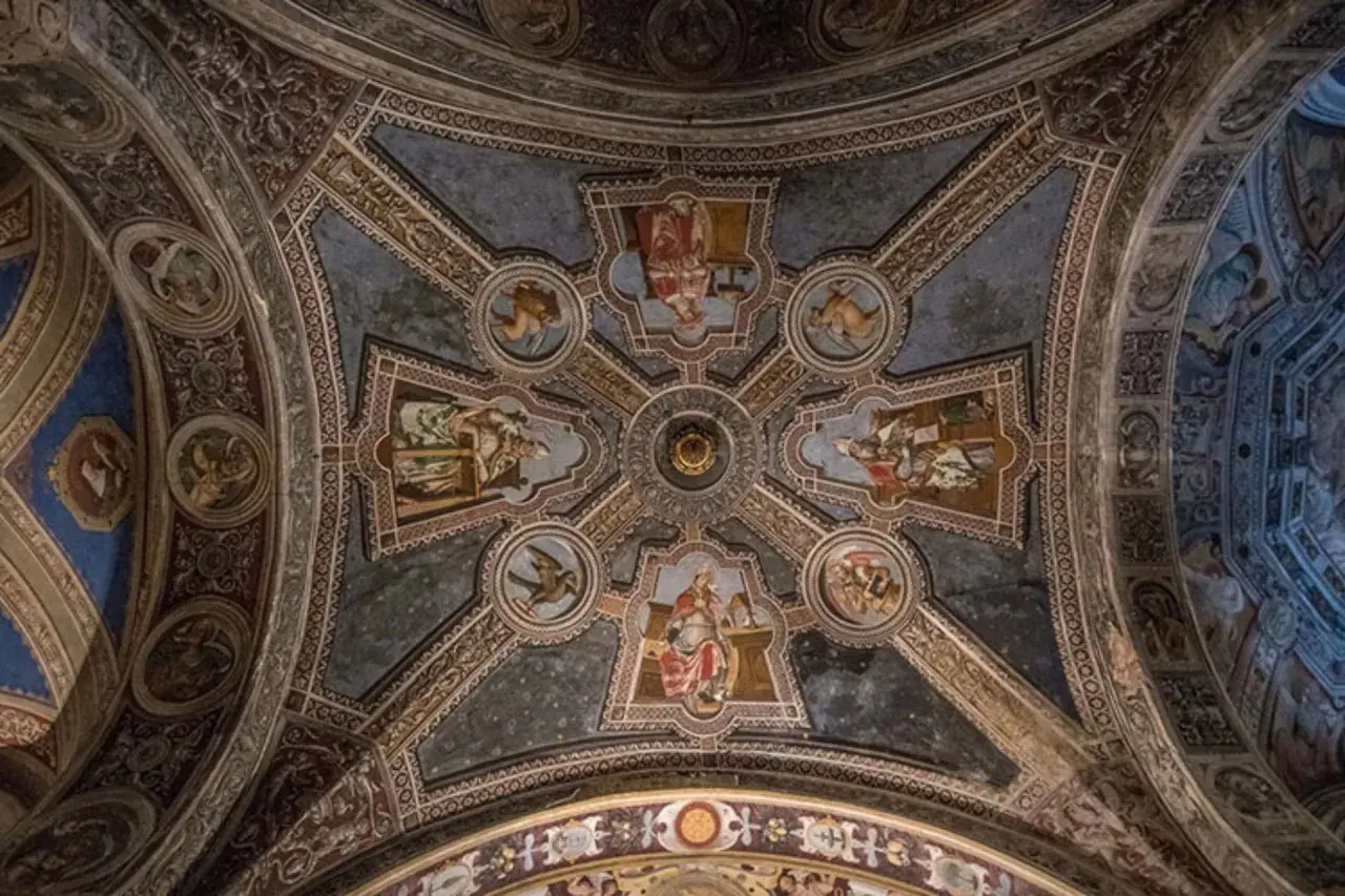 Volta affrescata di San Michele a Pavia, con scene bibliche e figure angeliche che adornano le volte a crociera, un capolavoro di arte medievale.