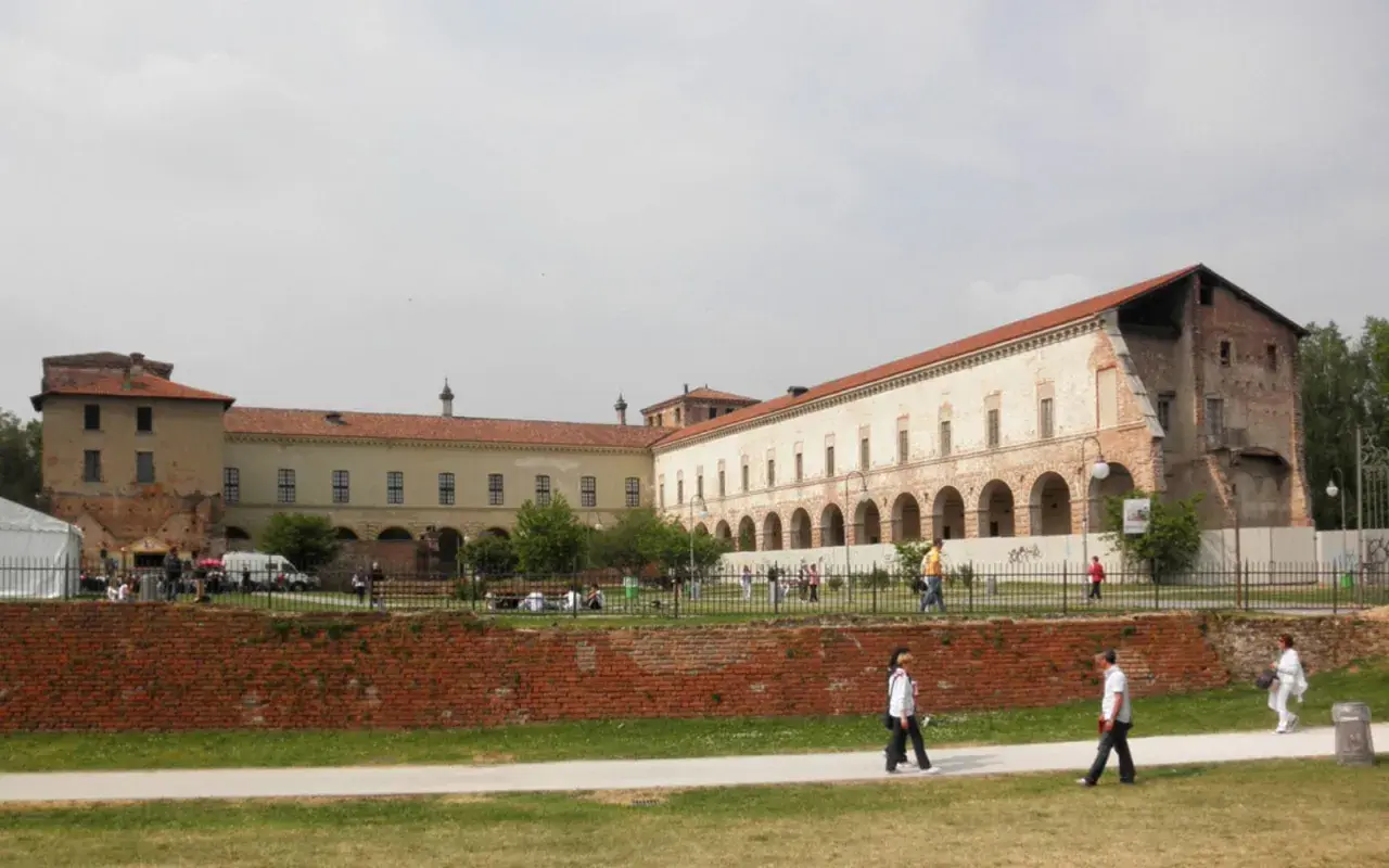 Il castello di Melegnano, con la sua architettura storica, accoglie visitatori e passeggiatori in una giornata nuvolosa.