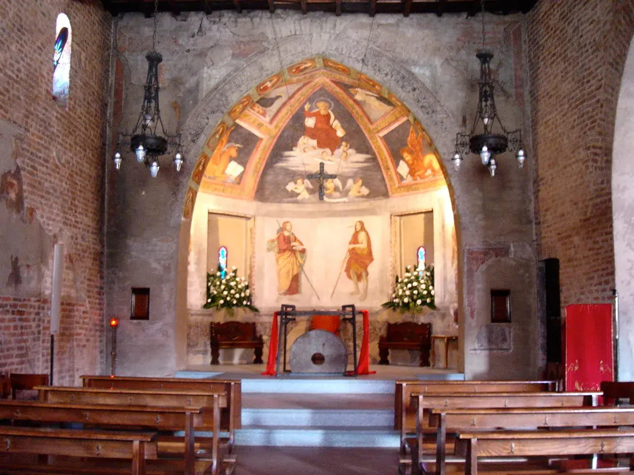 Interno di una chiesa con affreschi antichi e panche di legno. L'altare presenta un dipinto di San Cristoforo, simbolo di protezione per i viaggiatori a San Cristoforo, Milano.