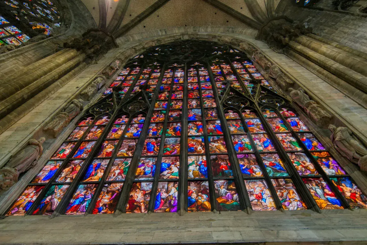Le vetrate del Duomo di Milano narrano storie sacre con colori vibranti, un capolavoro di arte gotica che illumina l'interno.
