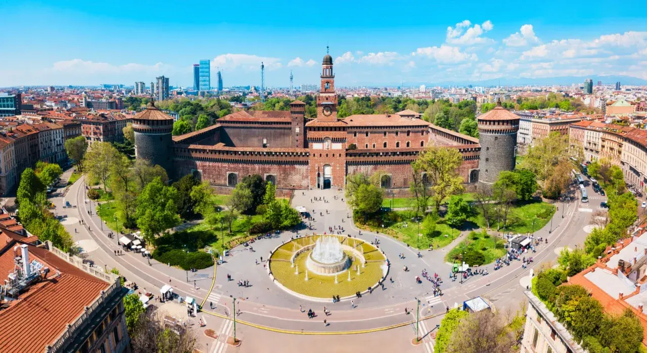 Il castello di Milano, imponente e storico, si erge maestoso con le sue torri e il cortile animato da visitatori.