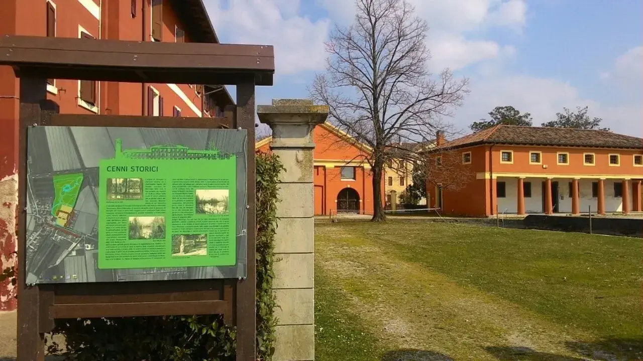 Cartello informativo sui cenni storici di Fossalta di Portogruaro, con edifici storici sullo sfondo.