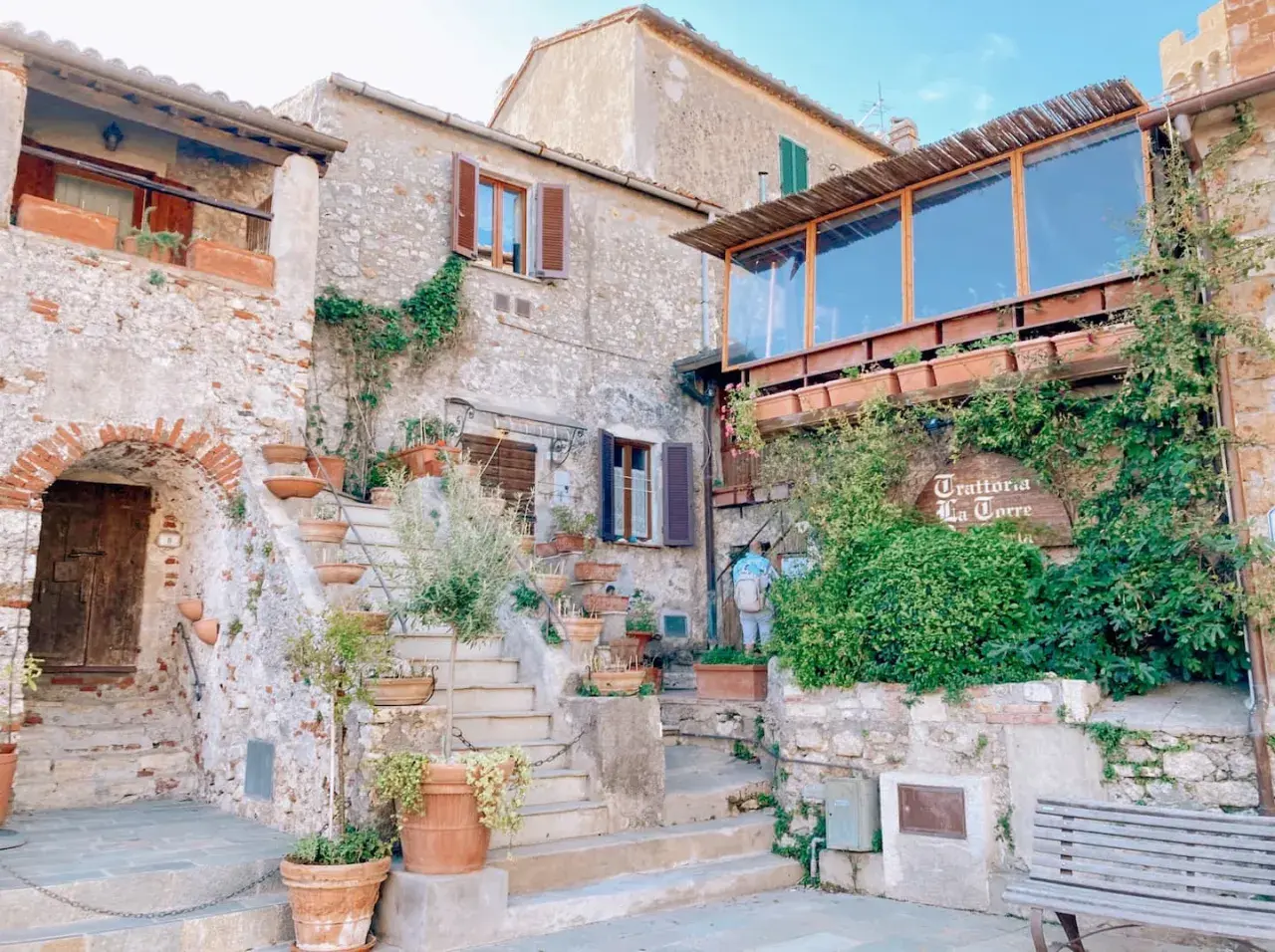 Un angolo incantevole tra i borghi vicino Capalbio, con scale di pietra, vasi di terracotta e la trattoria "La Torre" avvolta dal verde.