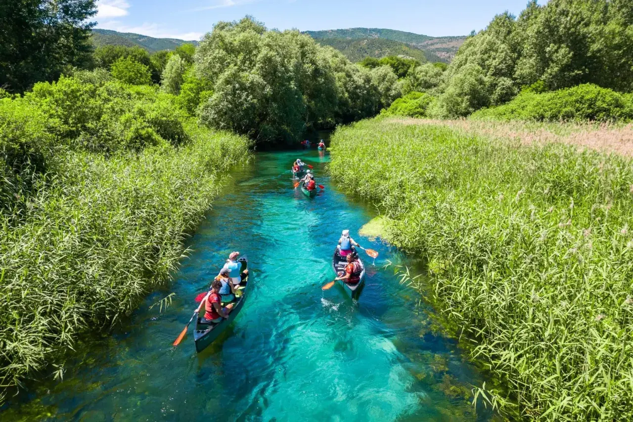 Persone in canoa su un fiume cristallino, un'ottima idea per visitare l'Abruzzo con itinerari naturalistici.