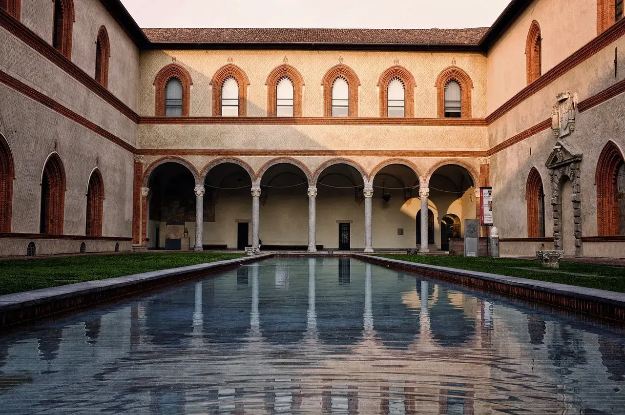 Cortile del Castello Sforzesco con piscina riflettente e portico ad archi.