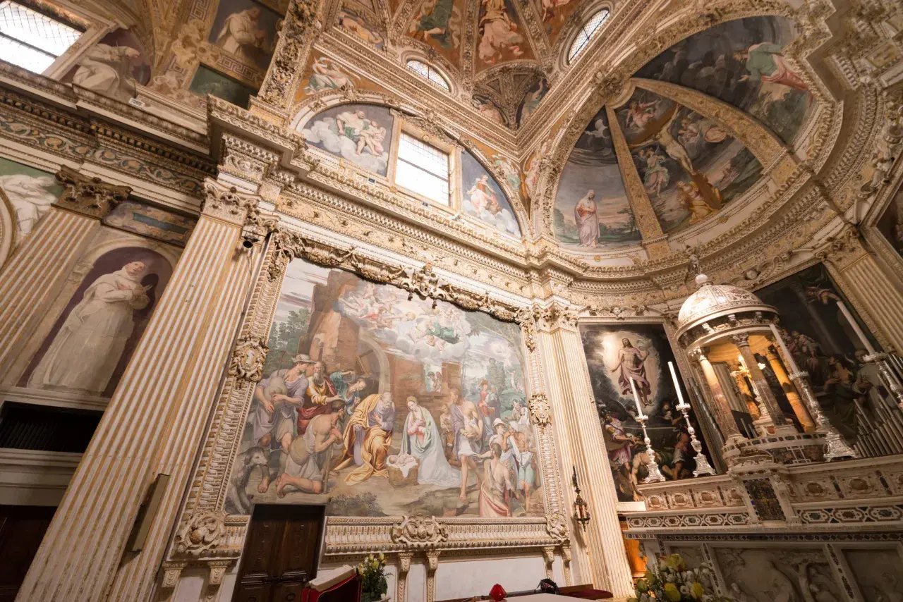 Interior of a church with ornate frescoes depicting religious scenes on walls and ceiling.