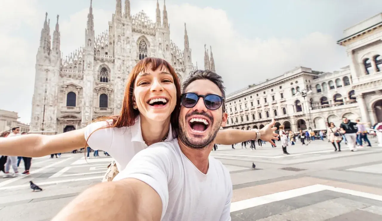 Coppia felice scatta un selfie a Milano, con il Duomo sullo sfondo. Perfetto per chi cerca visite guidate gratuite a Milano!