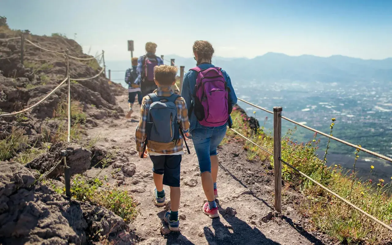 Famiglia in escursione sul sentiero del **Parco Nazionale del Vesuvio**, con vista panoramica sulla costa.