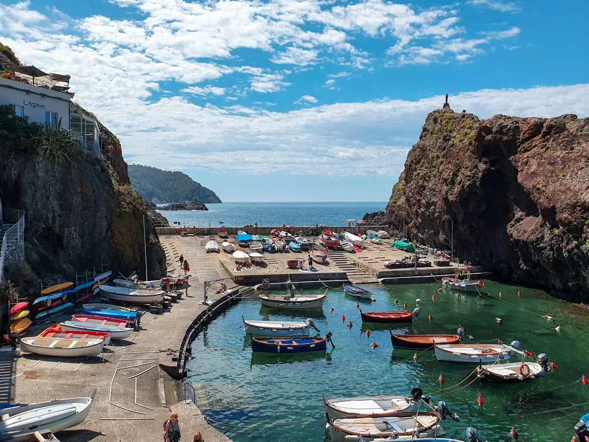 Un pittoresco porticciolo a **Framura, Liguria**, con barche colorate sull'acqua cristallina e scogliere a picco.