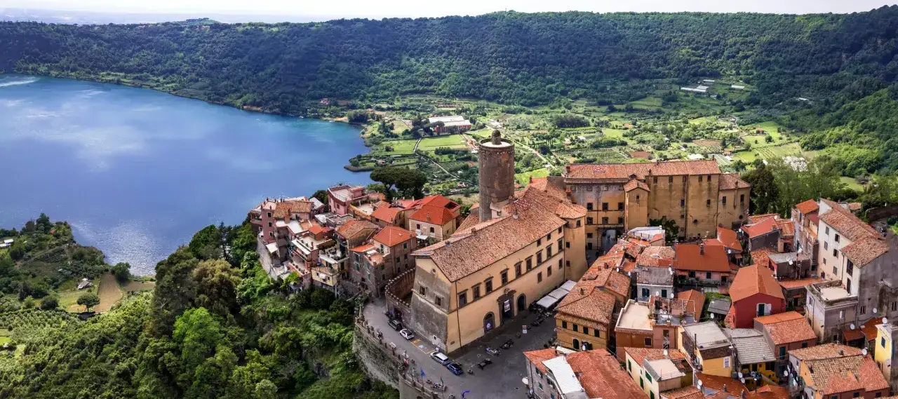 Nemi, un gioiello sui Castelli Romani, si affaccia sul lago. Case con tetti rossi si aggrappano alla collina, con una torre medievale che domina il panorama.