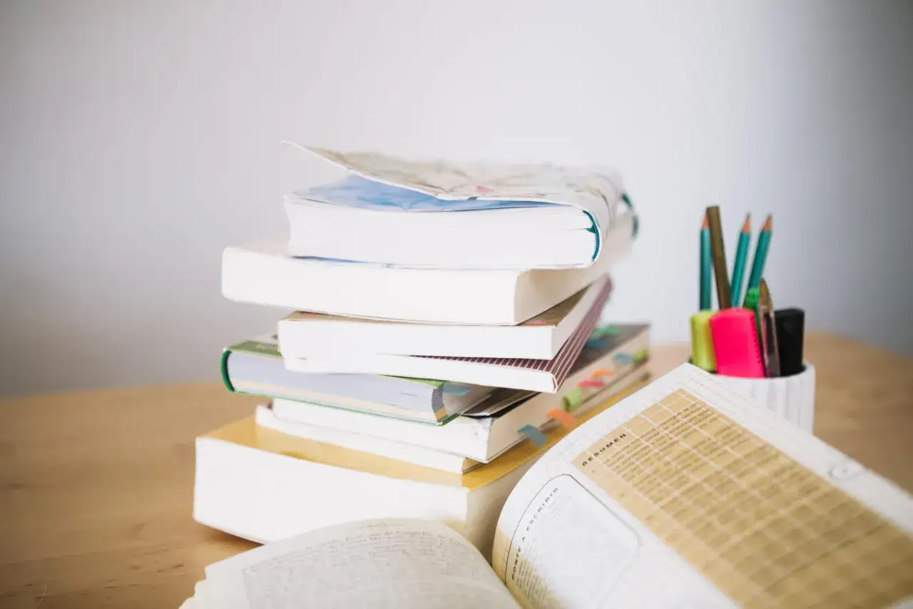 Pila di libri con segnalibri colorati e matite in un portapenne. Un vero bonus libri per chi ama studiare.