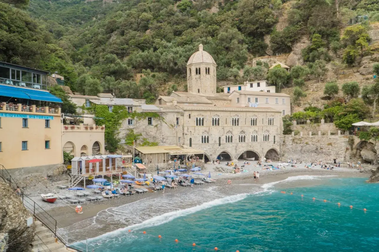 Baia di San Fruttuoso con spiaggia, mare turchese e l'abbazia. Ideale per il trekking e una pausa rilassante.