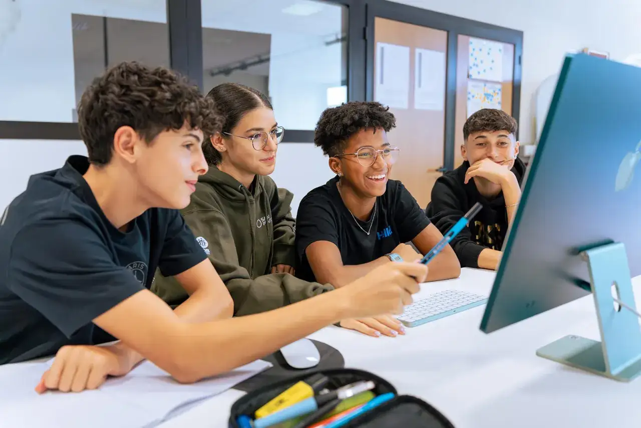 Giovani studenti collaborano a un progetto, puntando a un computer. Forse stanno preparando il loro diploma.