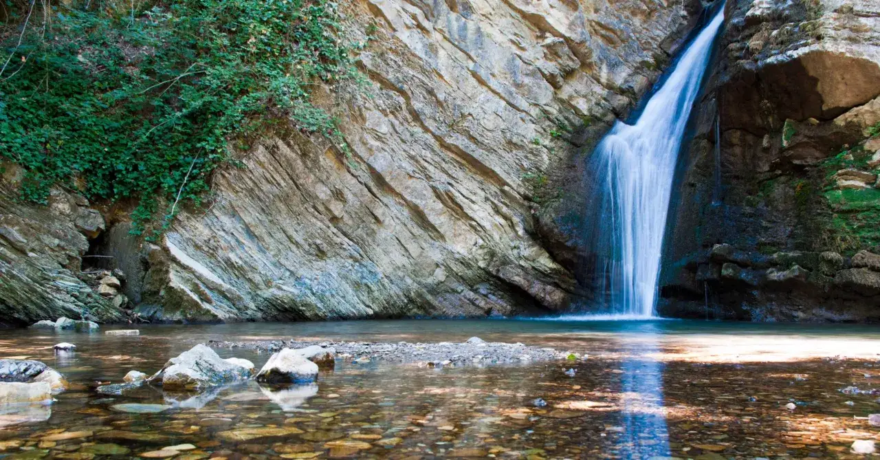 Cascate in Basilicata: acqua cristallina scende da rocce stratificate, circondate da vegetazione lussureggiante. Un angolo di paradiso naturale.