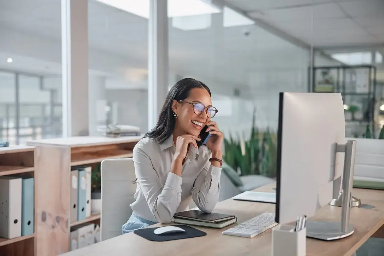 Donna sorridente al telefono in ufficio, felice per il suo dsga stipendio.
