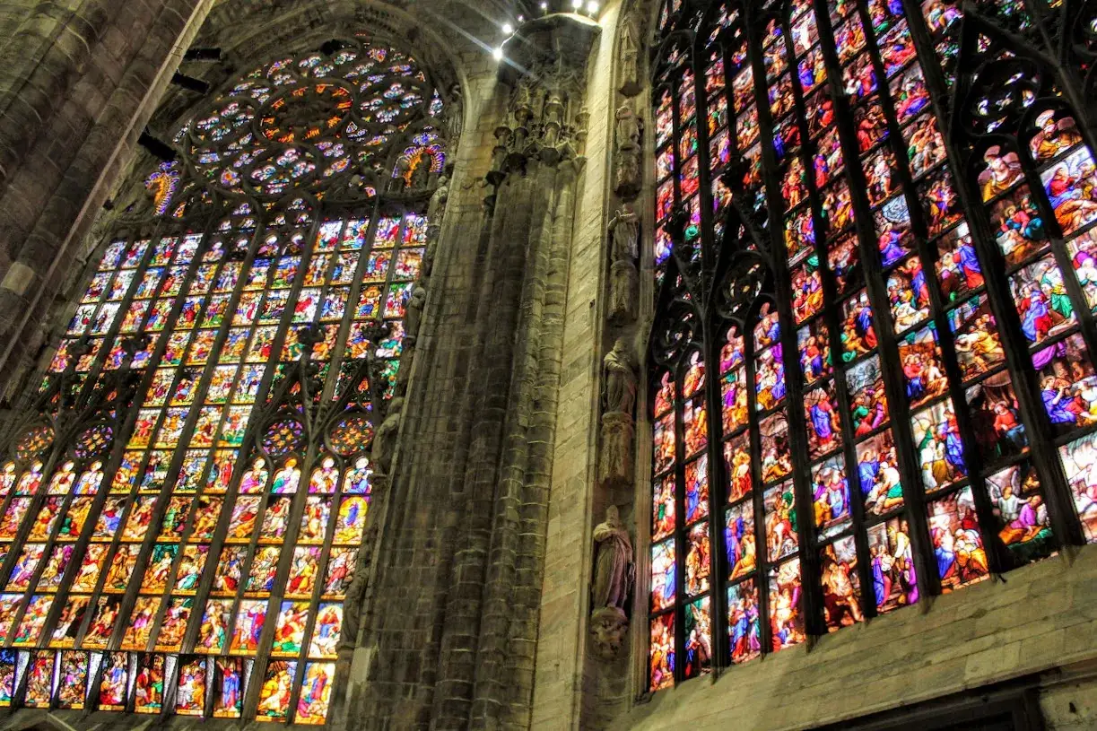 Le magnifiche vetrate del Duomo di Milano narrano storie sacre con colori vibranti, illuminando l'interno con una luce mistica.