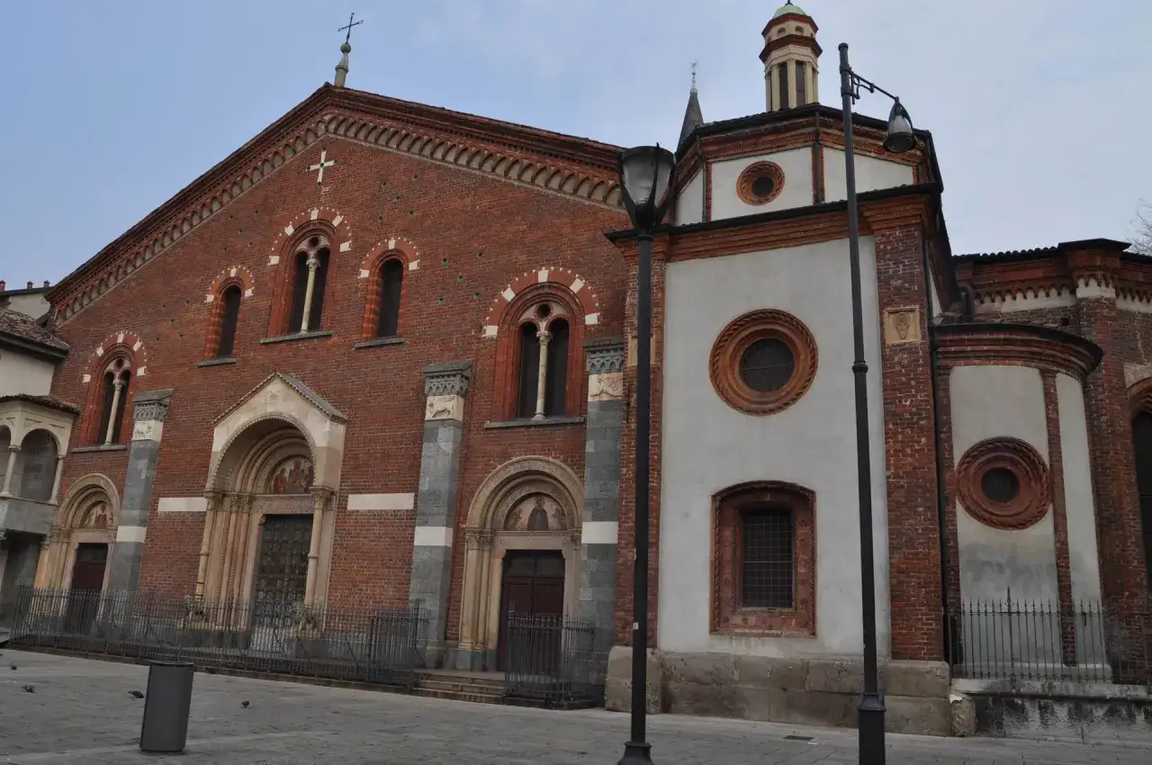 Facciata in mattoni rossi di Sant'Eustorgio a Milano, con portali in pietra e finestre ad arco.