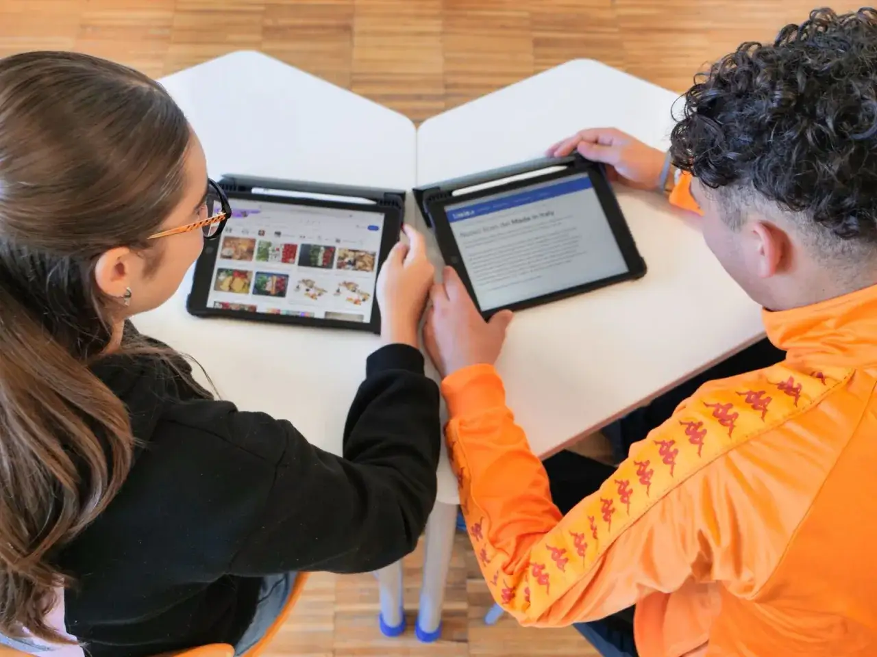 Due studenti collaborano su un progetto per il liceo del Made in Italy, studiando immagini e testi su tablet.
