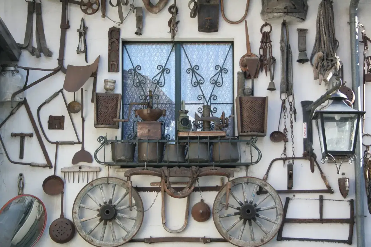 Attrezzi agricoli antichi e oggetti d'epoca decorano una parete a Bienno, Brescia.