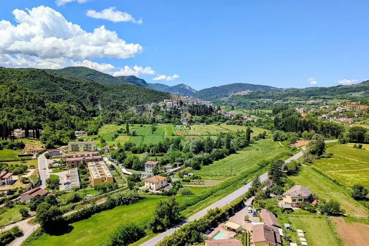 Panoramica di Arrone, Terni, con case sparse tra colline verdi e un borgo arroccato.