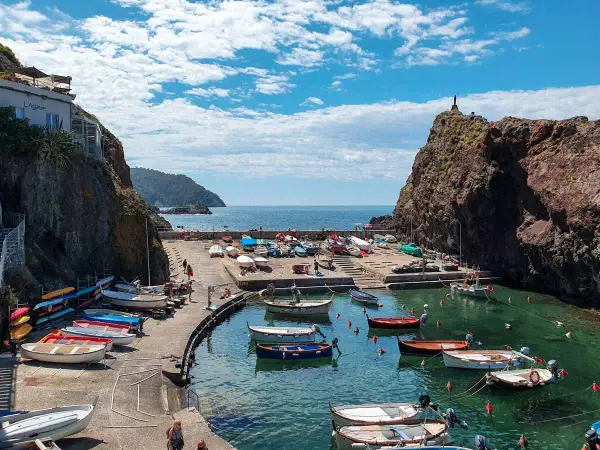 Un pittoresco porticciolo a **Framura, Liguria**, con barche colorate sull'acqua cristallina e scogliere a picco.